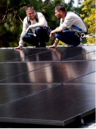 Two solar installers inspecting rooftop solar panels