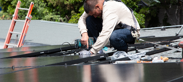 Professional works on roof installing solar panels to reduce electricity bills