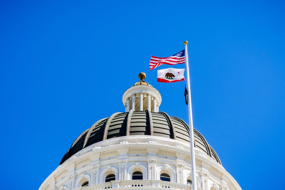 California flag waiting in front of the dome of the California State Capitol