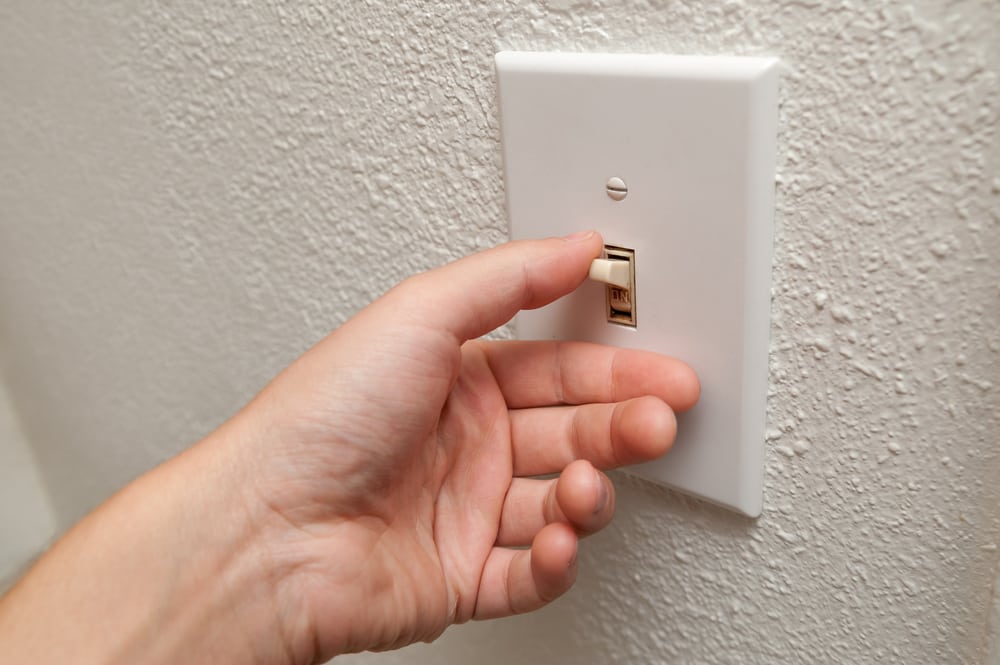 Hand turning off a light switch