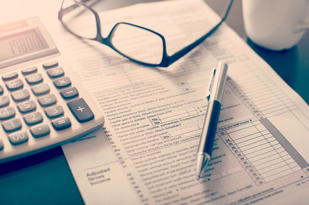 Tax documents with pen, calculator, and reading glasses