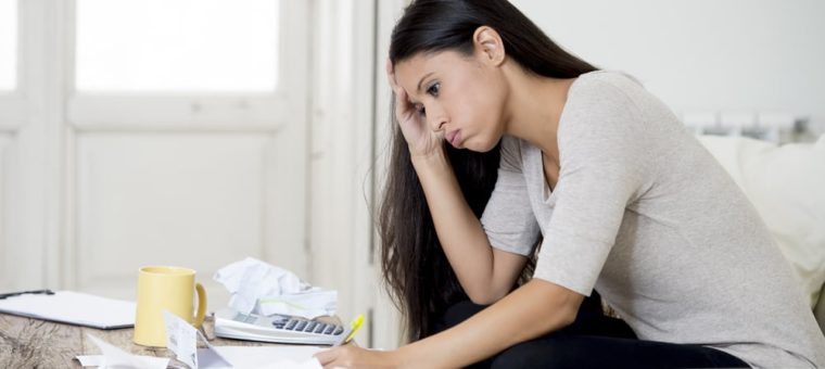 Young woman sitting at home, stressed about bills
