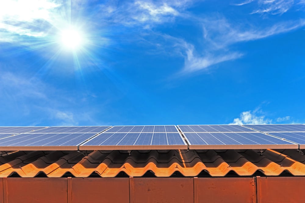 Solar panels on tile roof with sun overhead