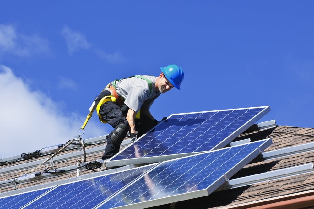 Worker installing solar panels for house