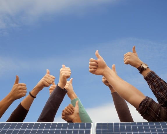 Multiple hands giving thumbs up behind solar panel