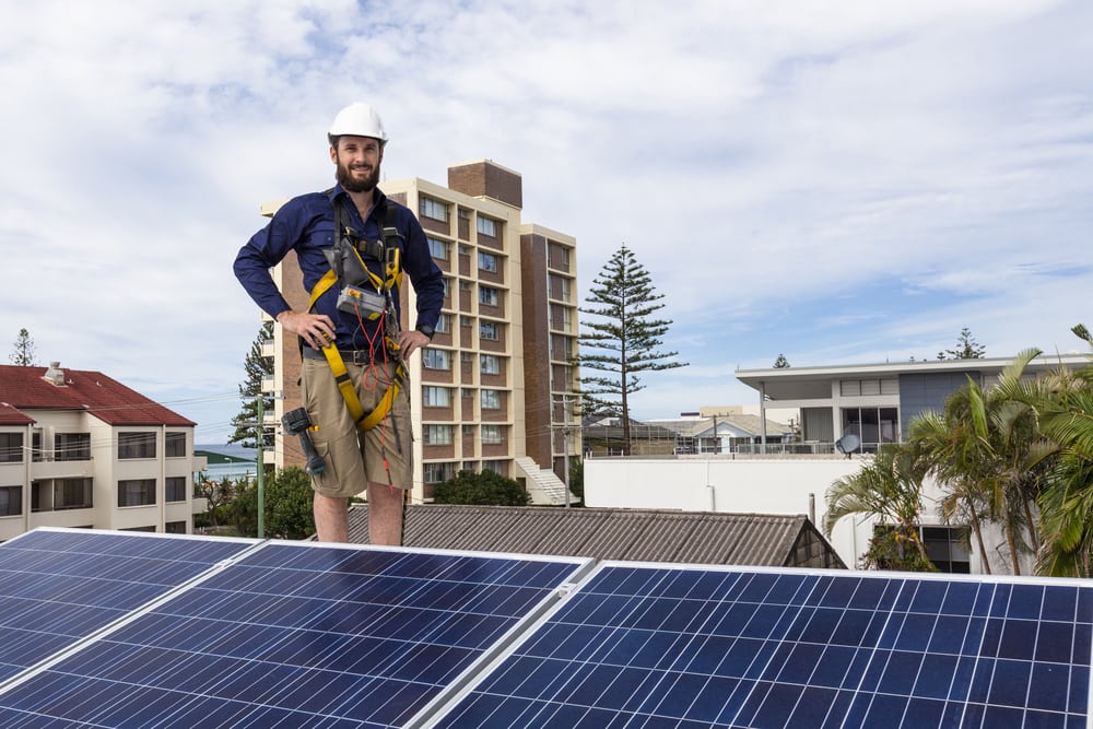 Solar installation contractor standing on roof after installing solar panels