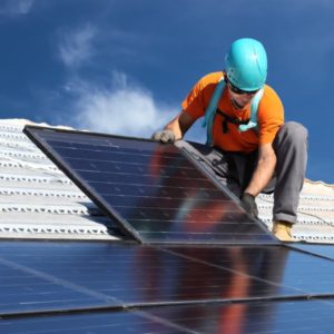 Worker installs solar panels on rooftop
