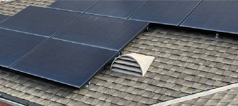 Nine solar panels on shingle roof with attic vent.