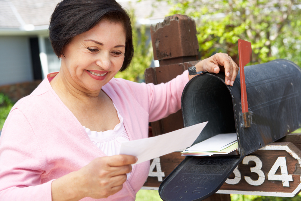 Woman reading mail from her mailbox.