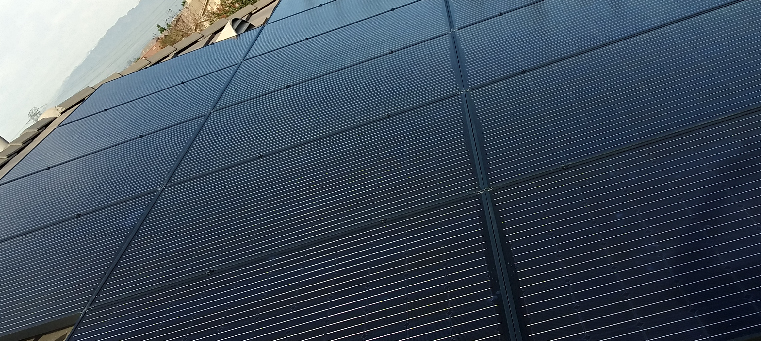 Solar panels covering roof of a single-family home with mountains in the distance.