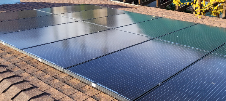 Twelve solar panels on an asphalt-shingle roof of a single-family home.
