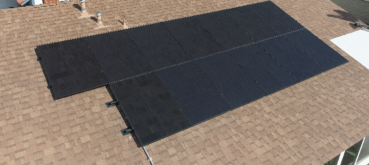 Thirteen solar panels on asphalt shingle roof of single story home.