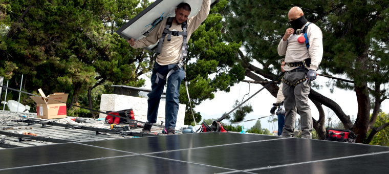 two-solar-panel-installers-on-roof-of-single-family-home