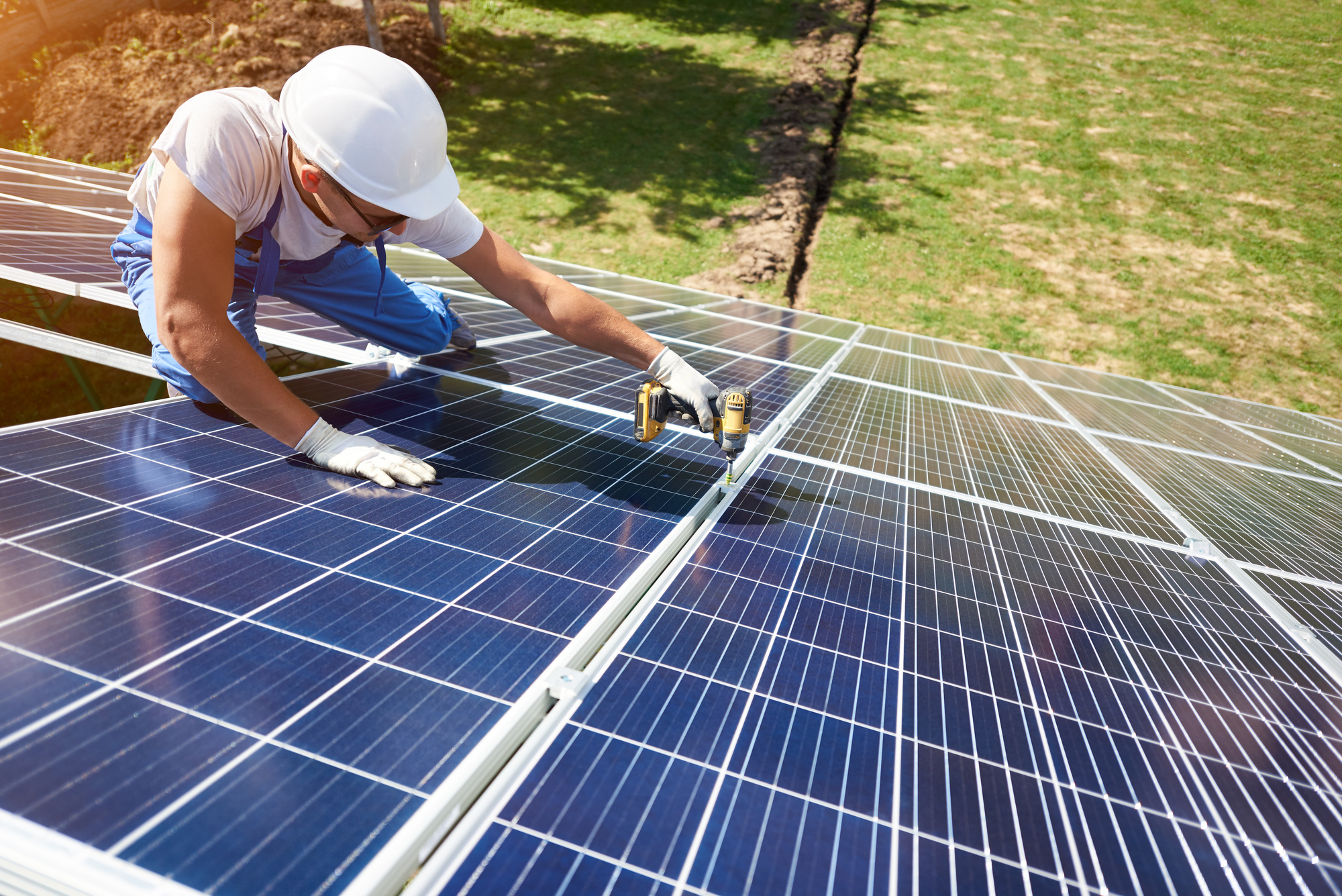 Professional worker installing solar panels on the green metal construction