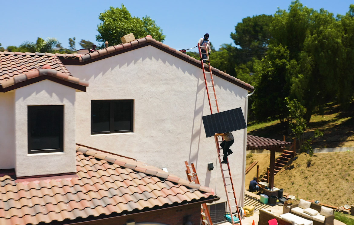 Solar Panel Installers Lifting Panel to Roof