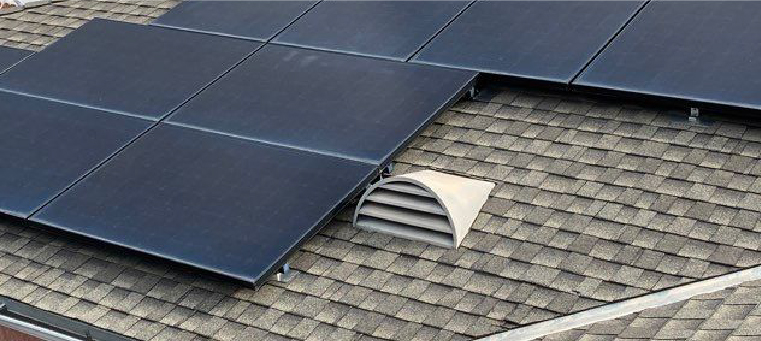 Nine solar panels on shingle roof with attic vent.